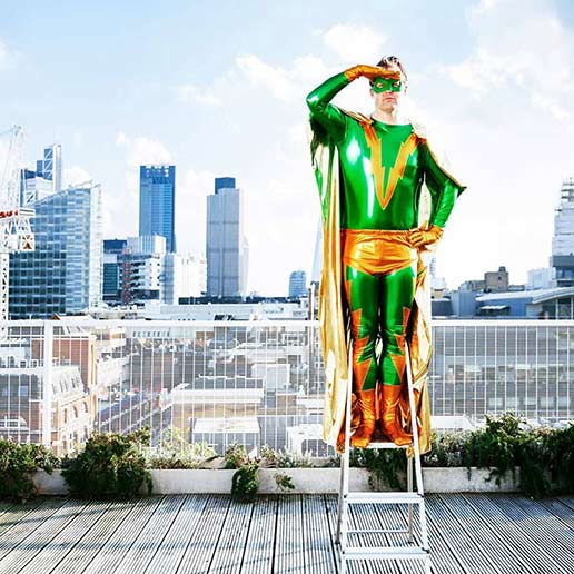 Superheld mit grün-goldenem Kostüm blickt von einer Leiter über eine Großstadt - symbolisiert Weitblick bei der Webentwicklung